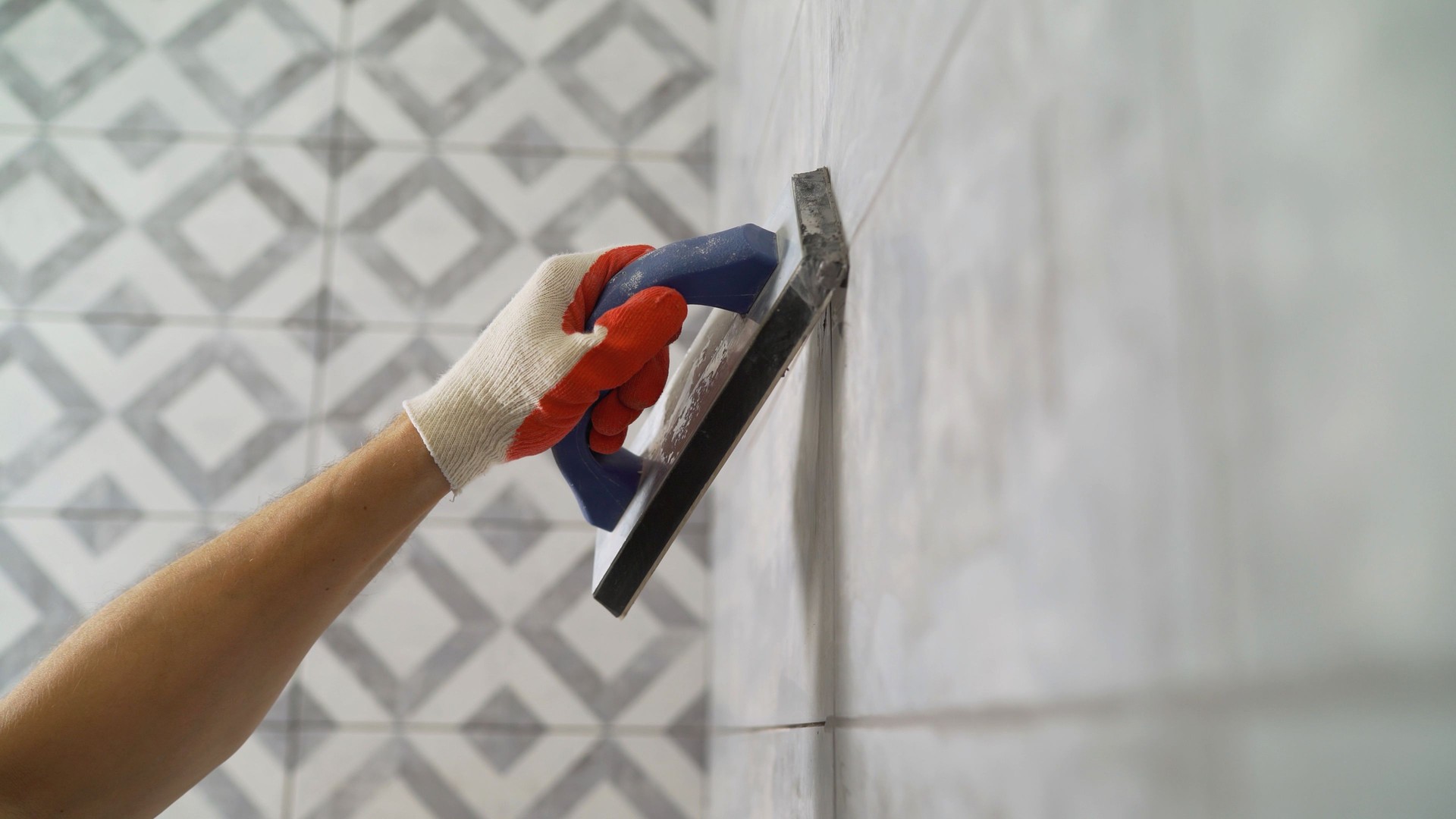Black grout for tiles. laying ceramic tiles. Tilers fill the spaces between tiles with a rubber trowel. Grout in the bathroom.